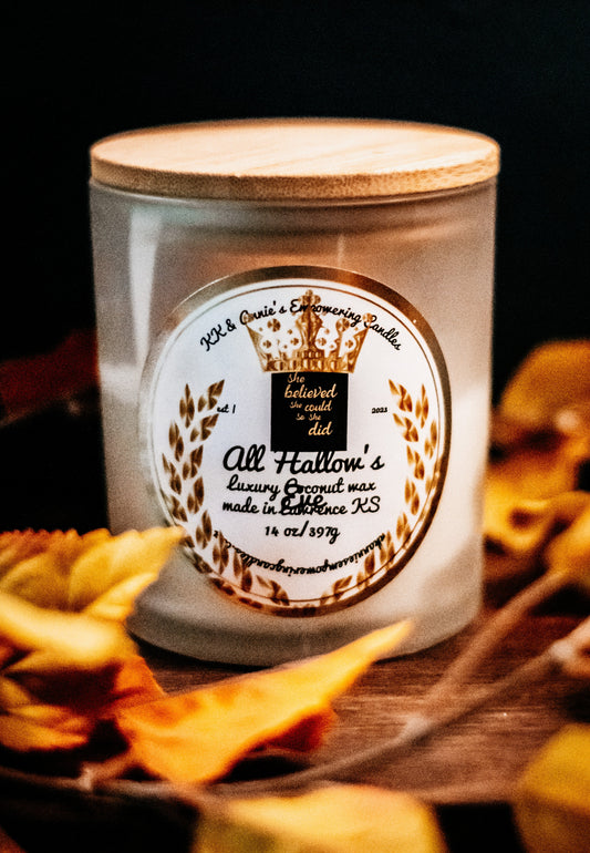 A close-up of the All Hallows Eve candle in a glass jar in a refined ambiance with a label that says KK & Annie's Empowering Candles, She believed she could so she did, with a golden Queen's crown.