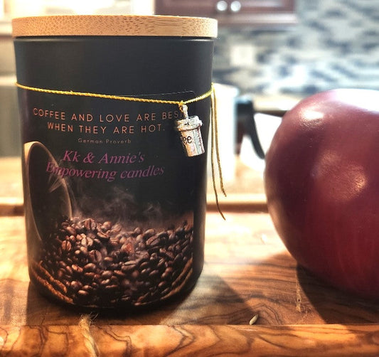 A close-up of the Campfire Coffee candle in a glass jar in a refined ambiance with a label that says KK & Annie's Empowering Candles, She believed she could so she did, with a golden Queen's crown.
